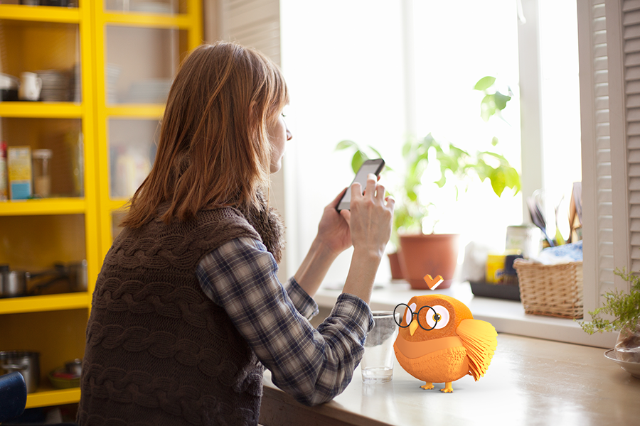 Une patiente consulte son mémo sur son smartphone à domicile, accompagnée de la mascotte Vulgaroo